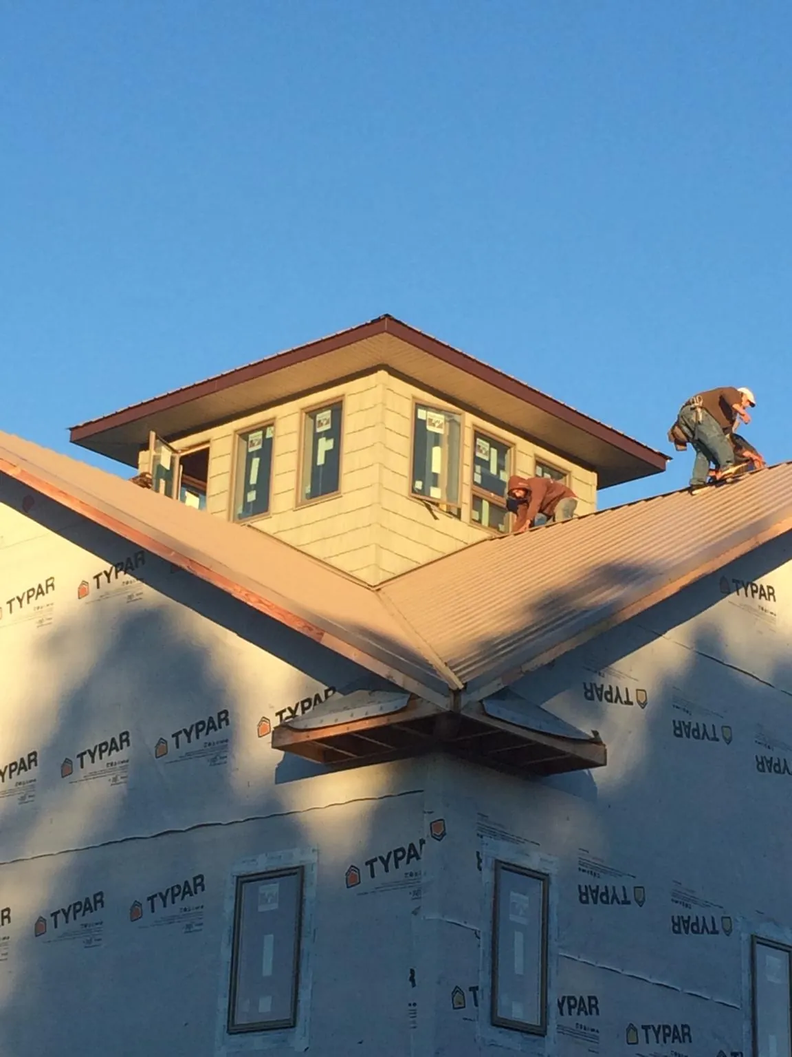 Roofers working around a rooftop cupola on a new metal roof at sunset — Roof Waterproofing in Shelby by Roofing Brothers